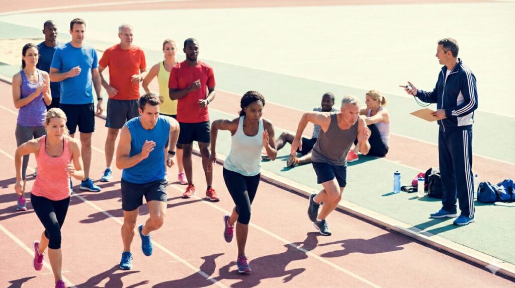 さまざまなレベルのランナーがトラックで閾値インターバルに取り組んでいる場面。初心者から上級者まで混在する雰囲気